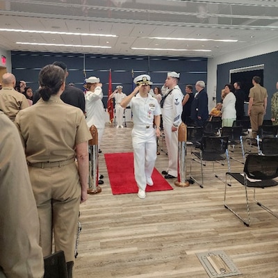 250910-O-NJ594-1181, Bethesda, Maryland, (August 22, 2025) -- Cmdr. Marshal Hoffman, outgoing officer in charge, Navy Bloodborne Infection Management Center salutes during a change of charge ceremony at United Service Organization (USO) in Bethesda, Maryland, Aug. 22, 2025. The event honored Hoffman’s accomplishments and welcomed Sklar as the new officer in charge, reaffirming the center’s role in medical readiness, force health protection, and compassionate care for service members. (U.S. Navy photo by Ai Marrero)