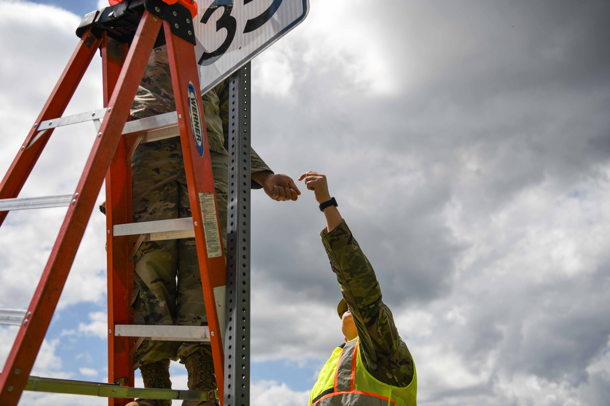 Service members replace a speed limit sign.