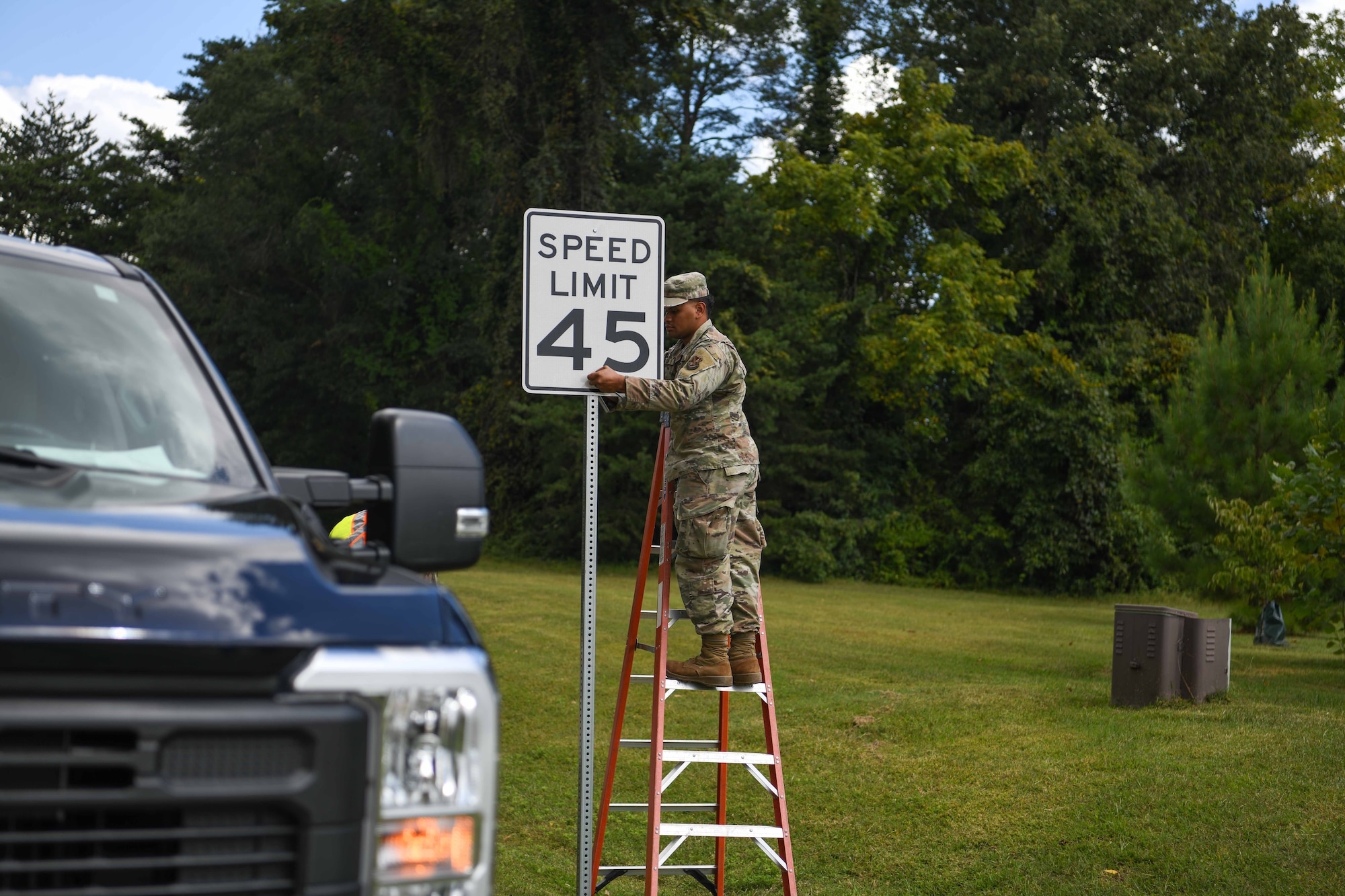 Service members replace a speed limit sign.