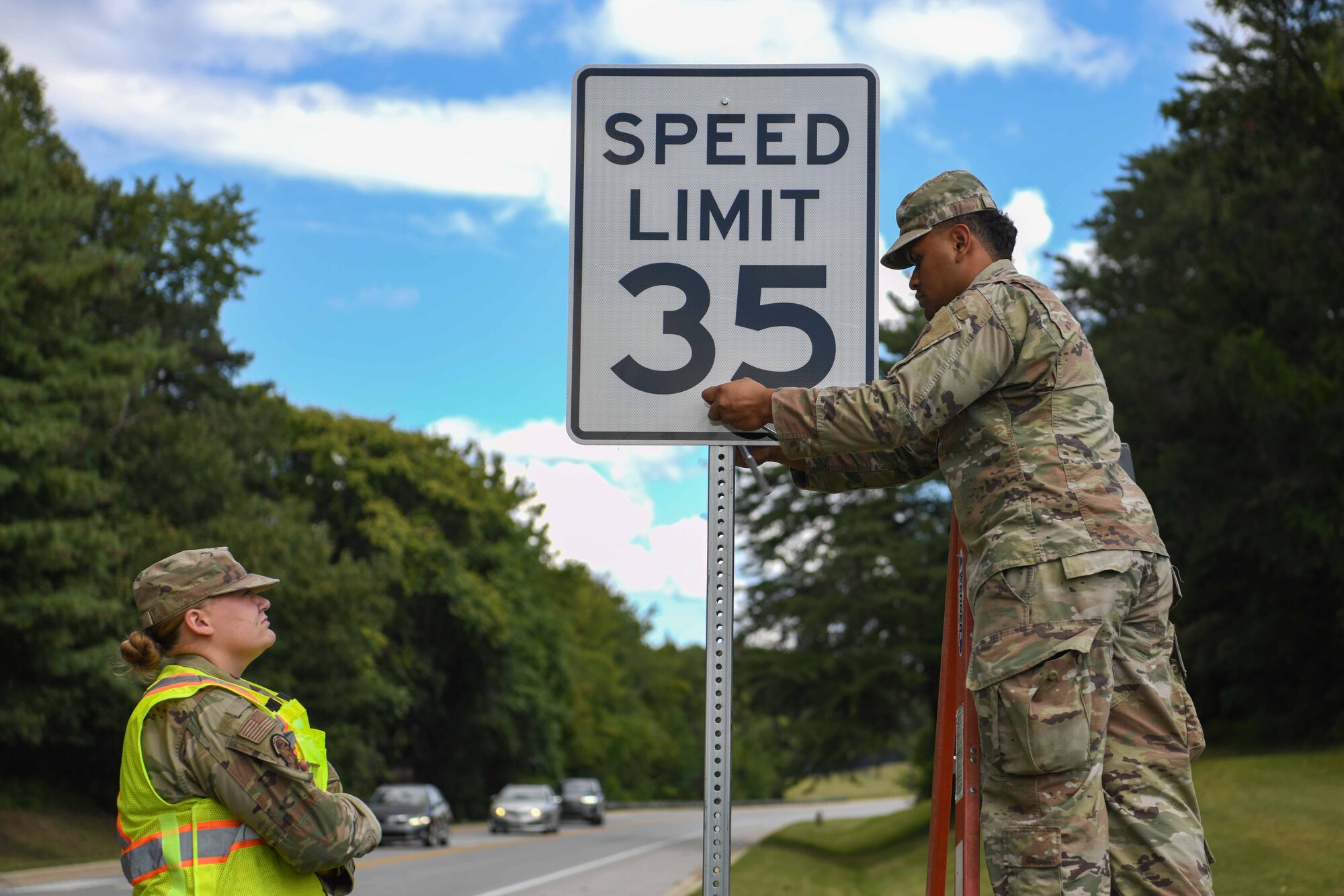 Service members replace a speed limit sign.