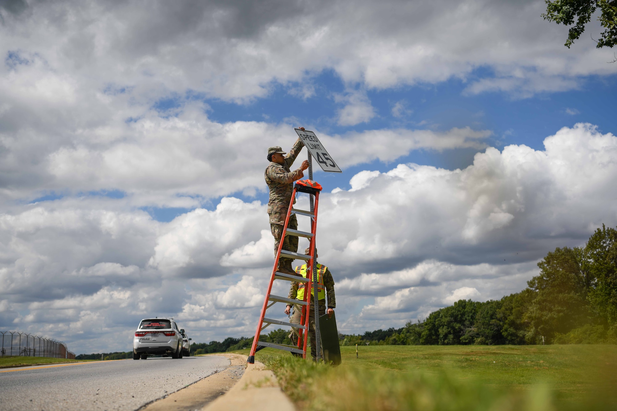 Service members replace a speed limit sign.