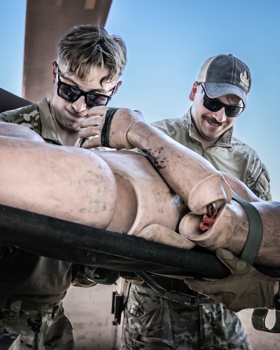 U.S. Air Force Senior Airmen Jack Roscoe (left) and Seth Elroy (right), 56th Civil Engineer Squadron explosive ordnance disposal technicians, offload a rescue manikin from an Army UH-60 Blackhawk helicopter