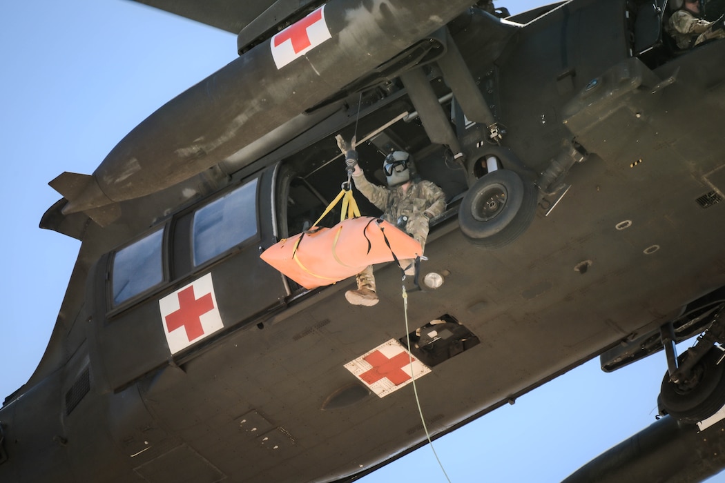 U.S Army Spc. Tyler Robertson, a crew chief assigned to Charlie Company, 2nd General Support Aviation Battalion, 1st Aviation Regiment, 1st Combat Aviation Brigade, 1st Infantry Division, receives a rescue manikin via hoist