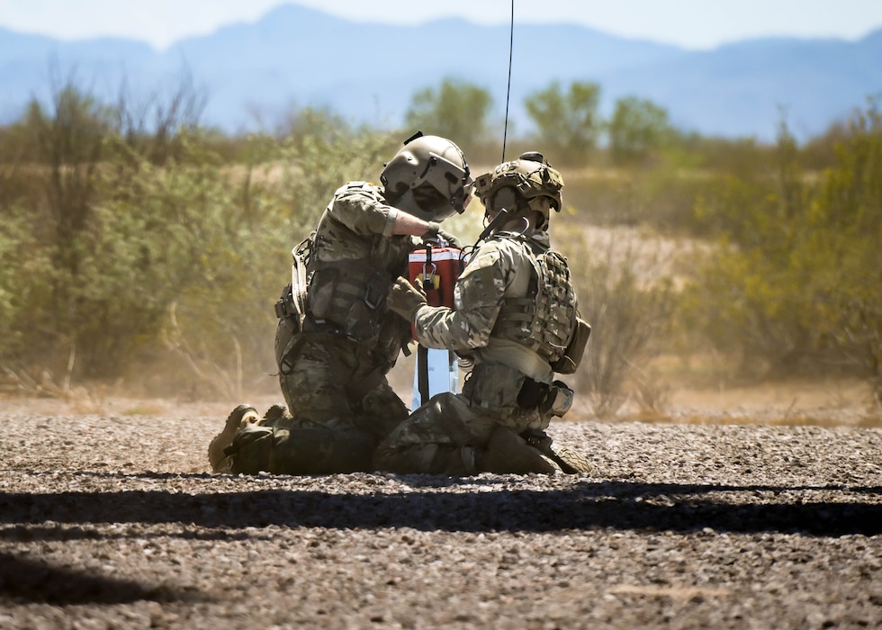 U.S. Army Staff Sgt. Cody Solomon (left), a flight paramedic assigned to Charlie Company, 2nd General Support Aviation Battalion, 1st Aviation Regiment, 1st Combat Aviation Brigade, 1st Infantry Division, secures U.S. Air Force Senior Airman Elias Saavedra (right), 56th Civil Engineer Squadron explosive ordnance disposal technician, into a 420 rescue seat for a hover hoist operation from a moving aircraft