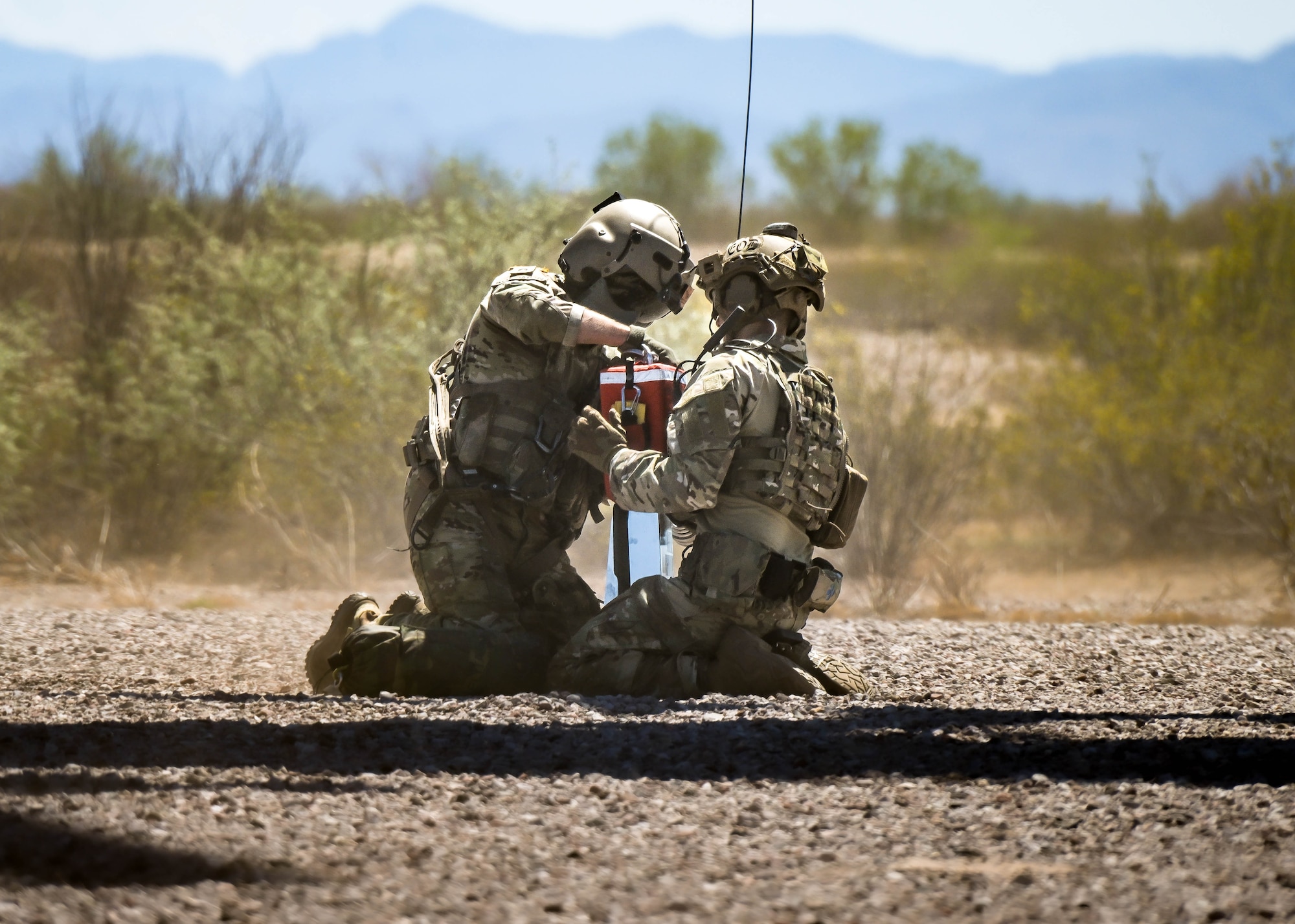 U.S. Army Staff Sgt. Cody Solomon (left), a flight paramedic assigned to Charlie Company, 2nd General Support Aviation Battalion, 1st Aviation Regiment, 1st Combat Aviation Brigade, 1st Infantry Division, secures U.S. Air Force Senior Airman Elias Saavedra (right), 56th Civil Engineer Squadron explosive ordnance disposal technician, into a 420 rescue seat for a hover hoist operation from a moving aircraft