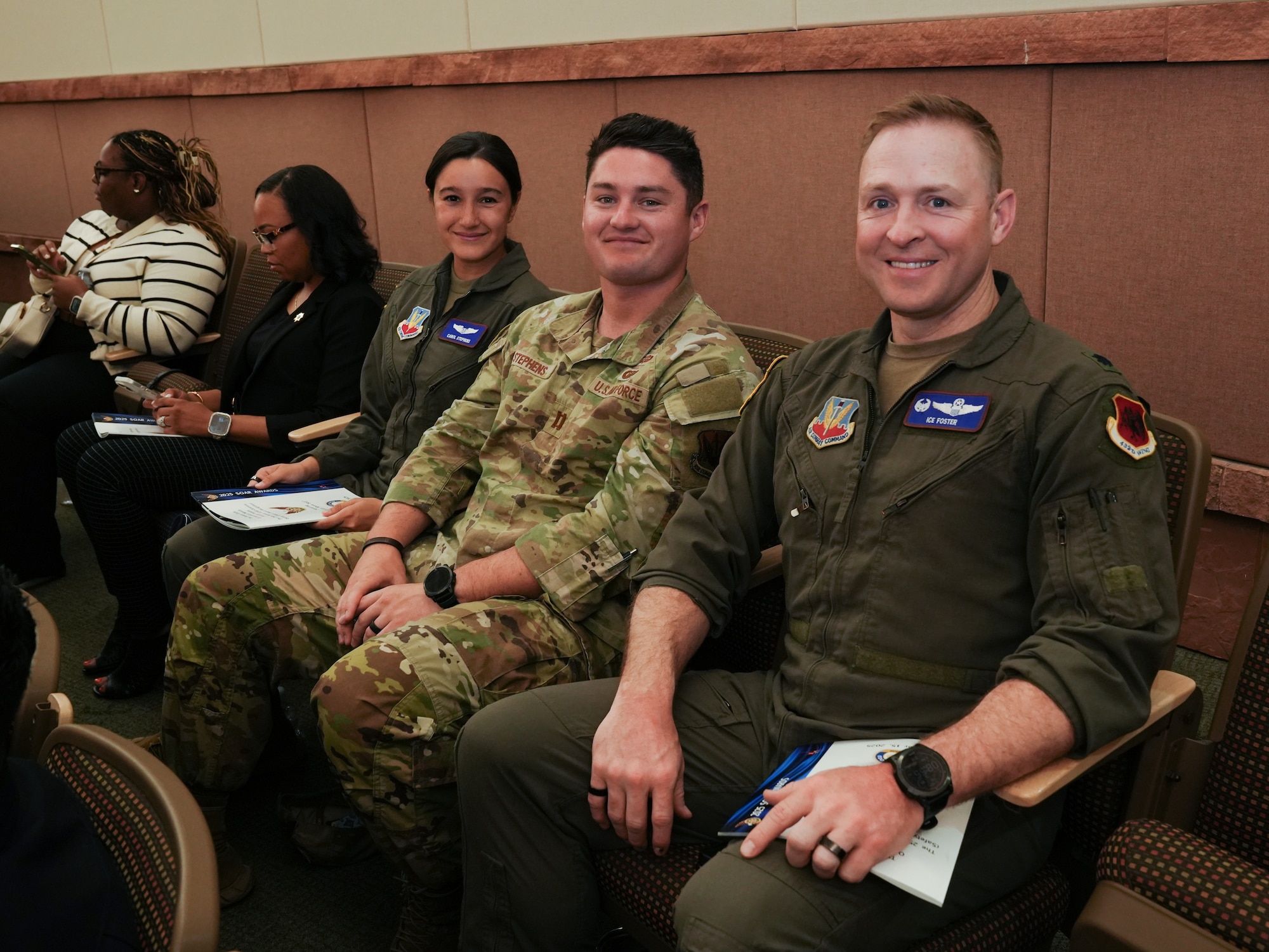 Three people in military uniforms are seated and smiling for a photo.