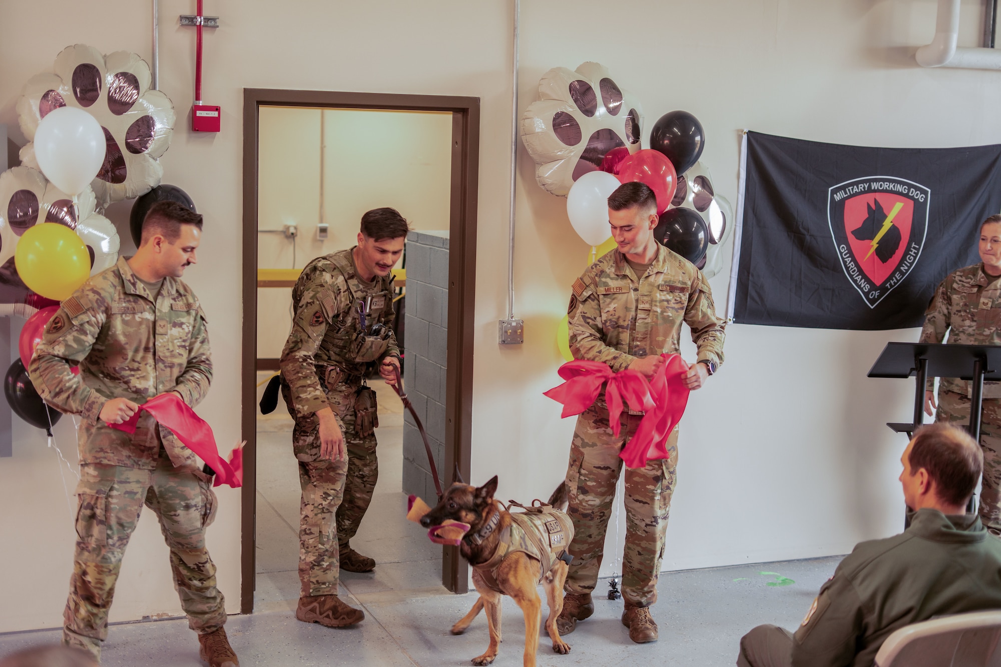 U.S. Air Force Senior Airman Drake Sherman, left, Staff Sgt. Alex Petkovic, middle, and Senior Airman Stone Miller, right, 354th Security Forces Squadron Military Working Dog handlers, cut the ceremonial ribbon for the newly renovated facility during a K9 kennel ribbon cutting ceremony at Eielson Air Force Base, Alaska, Sept. 12, 2025.