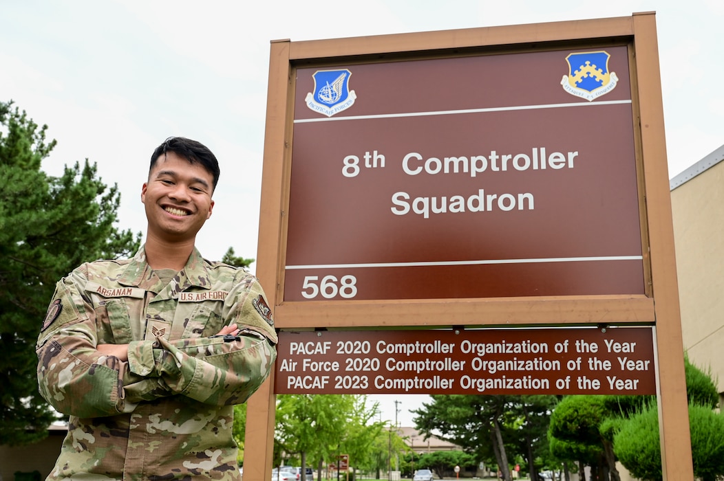 A man poses in fron tof a sign.
