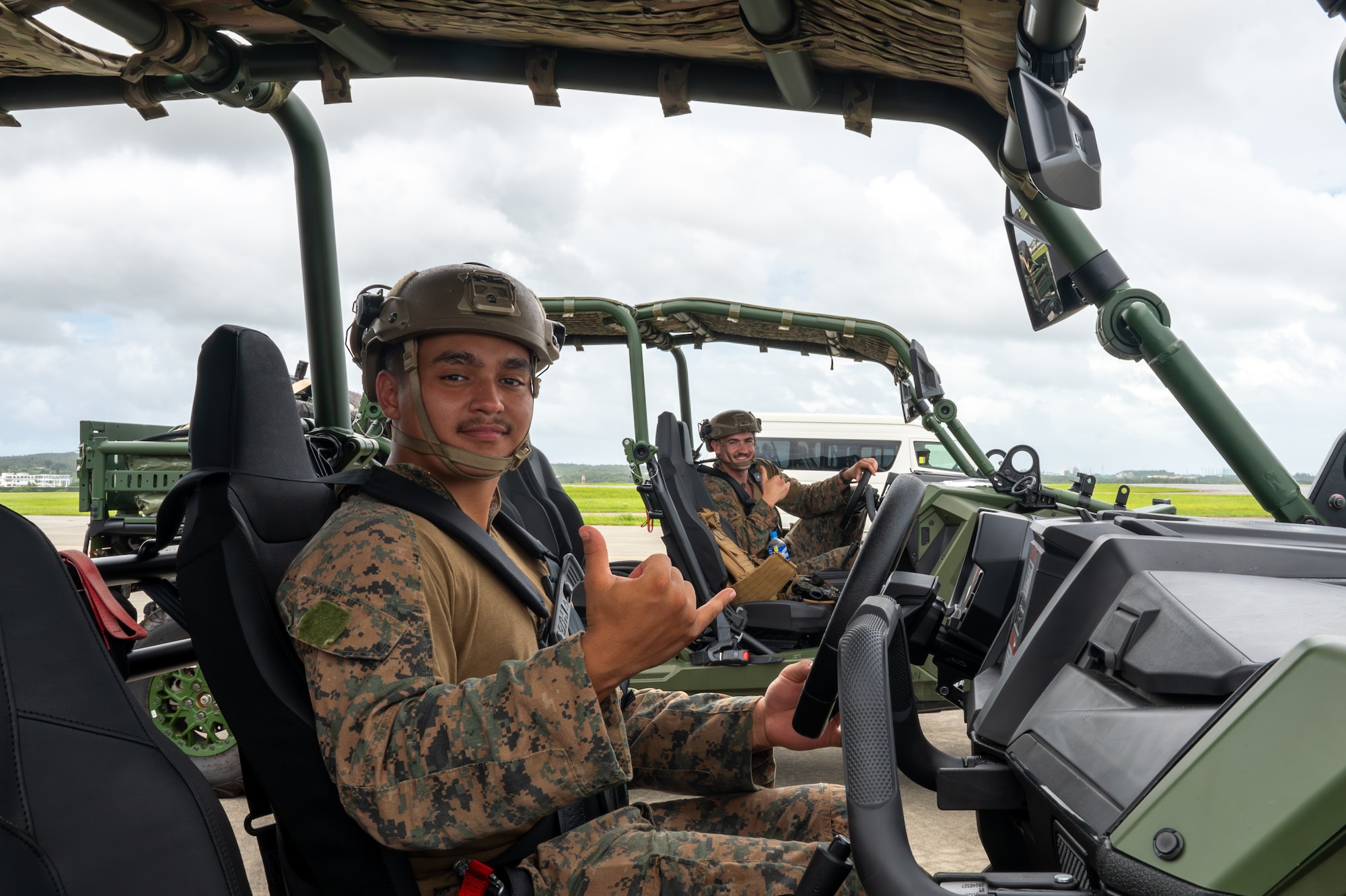 Service member pose for a photo while being inside of a military vehicle.