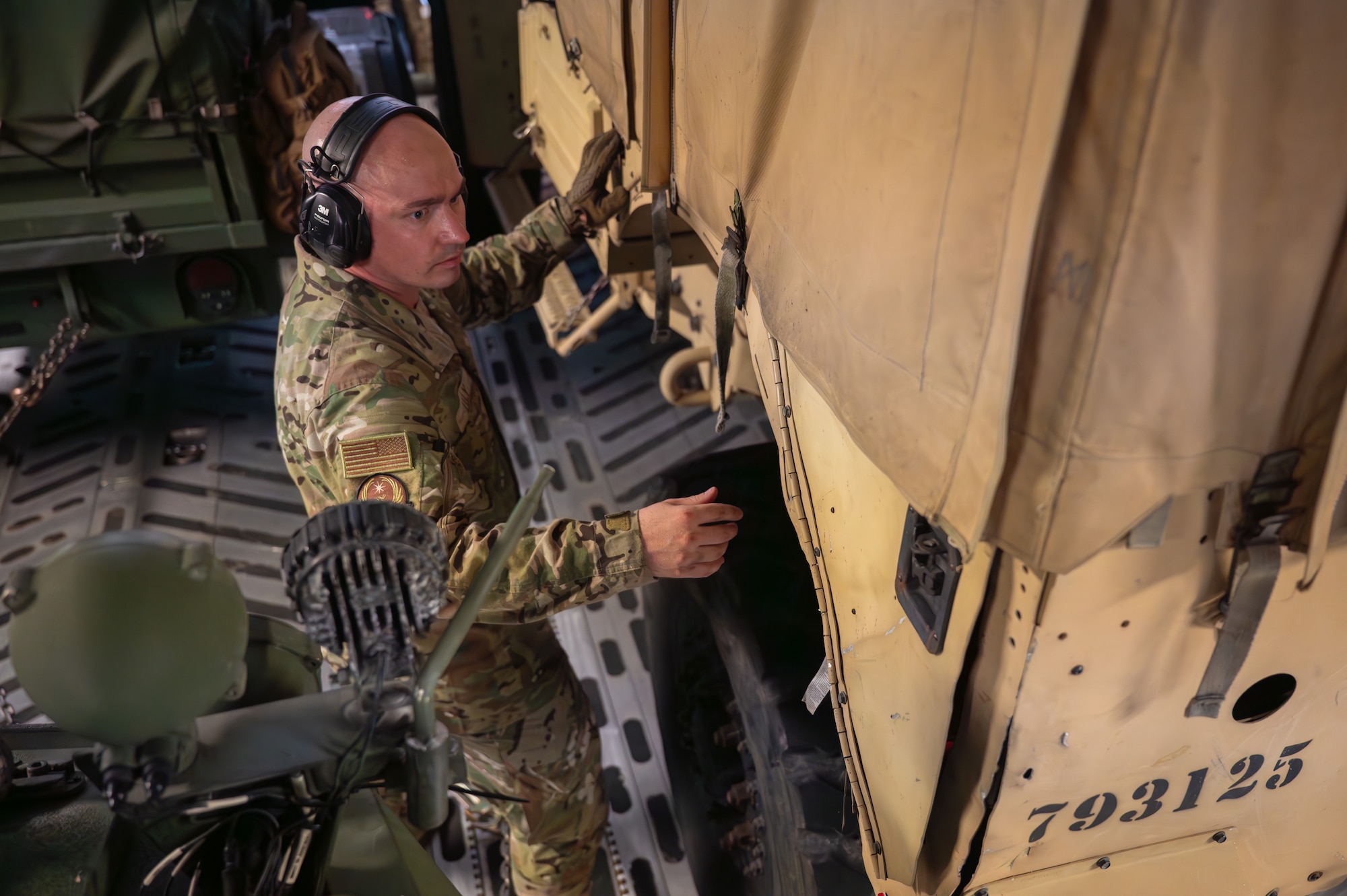A service member is inspecting a military vehicle.