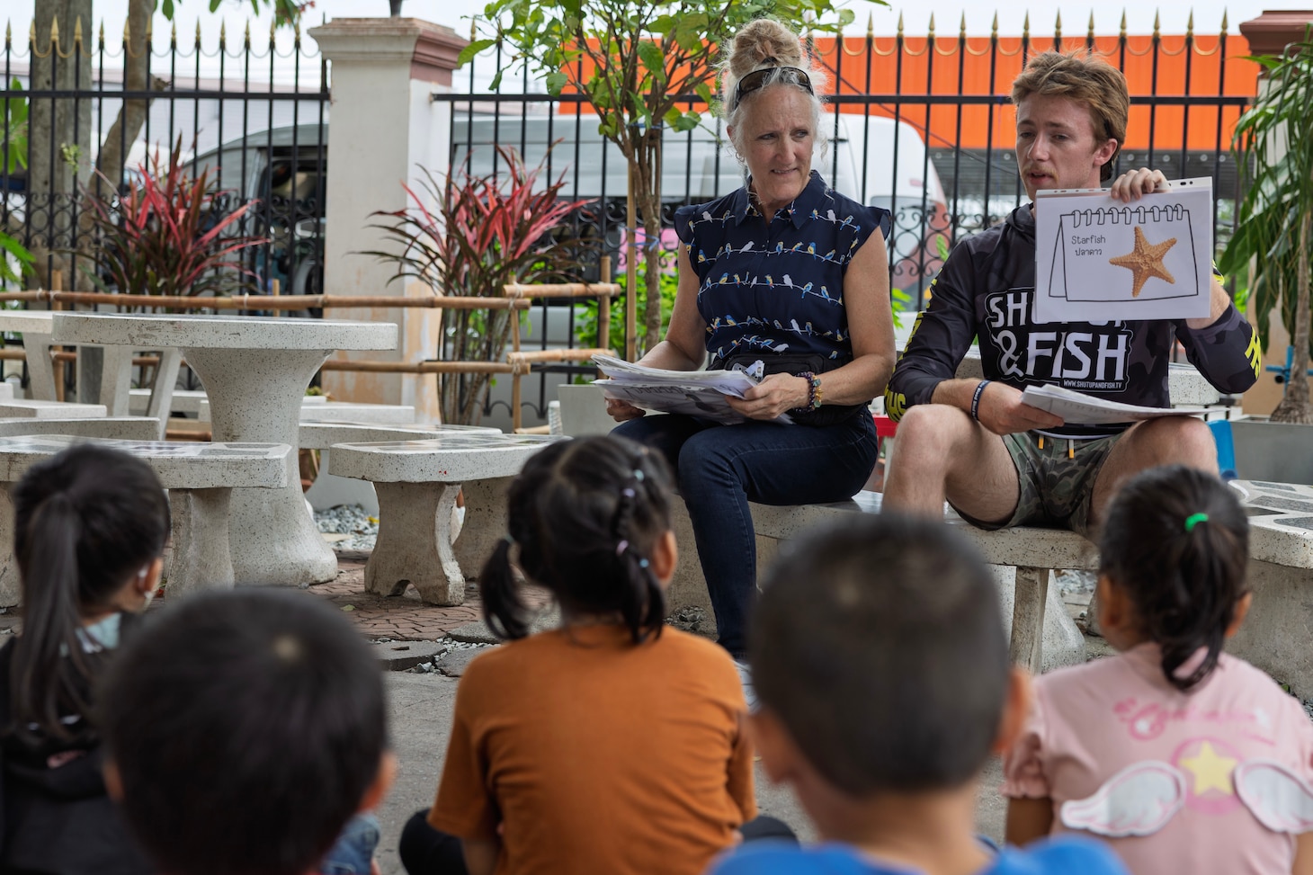 Civilian mariners Nora Riley, supply utilityman, and Samuel Cannon, ordinary seaman, assigned to Lewis and Clark-class dry cargo ship USNS Amelia Earhart (T-AKE 6), teach English to children of the Fountain of Life Children’s Center in Pattaya, Thailand, during a community outreach event, Sept. 10.