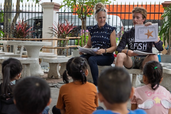 Civilian mariners Nora Riley, supply utilityman, and Samuel Cannon, ordinary seaman, assigned to Lewis and Clark-class dry cargo ship USNS Amelia Earhart (T-AKE 6), teach English to children of the Fountain of Life Children’s Center in Pattaya, Thailand, during a community outreach event, Sept. 10.
