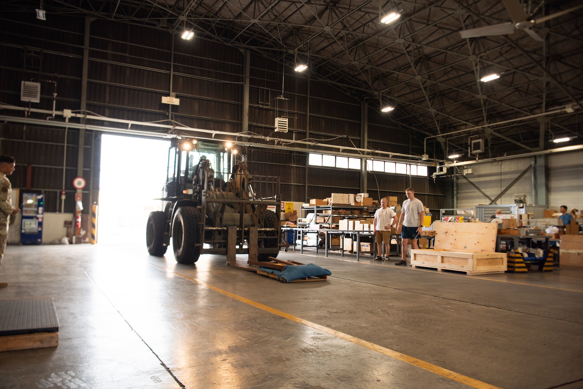 A forklift vehicle carries a plaque into a hangar