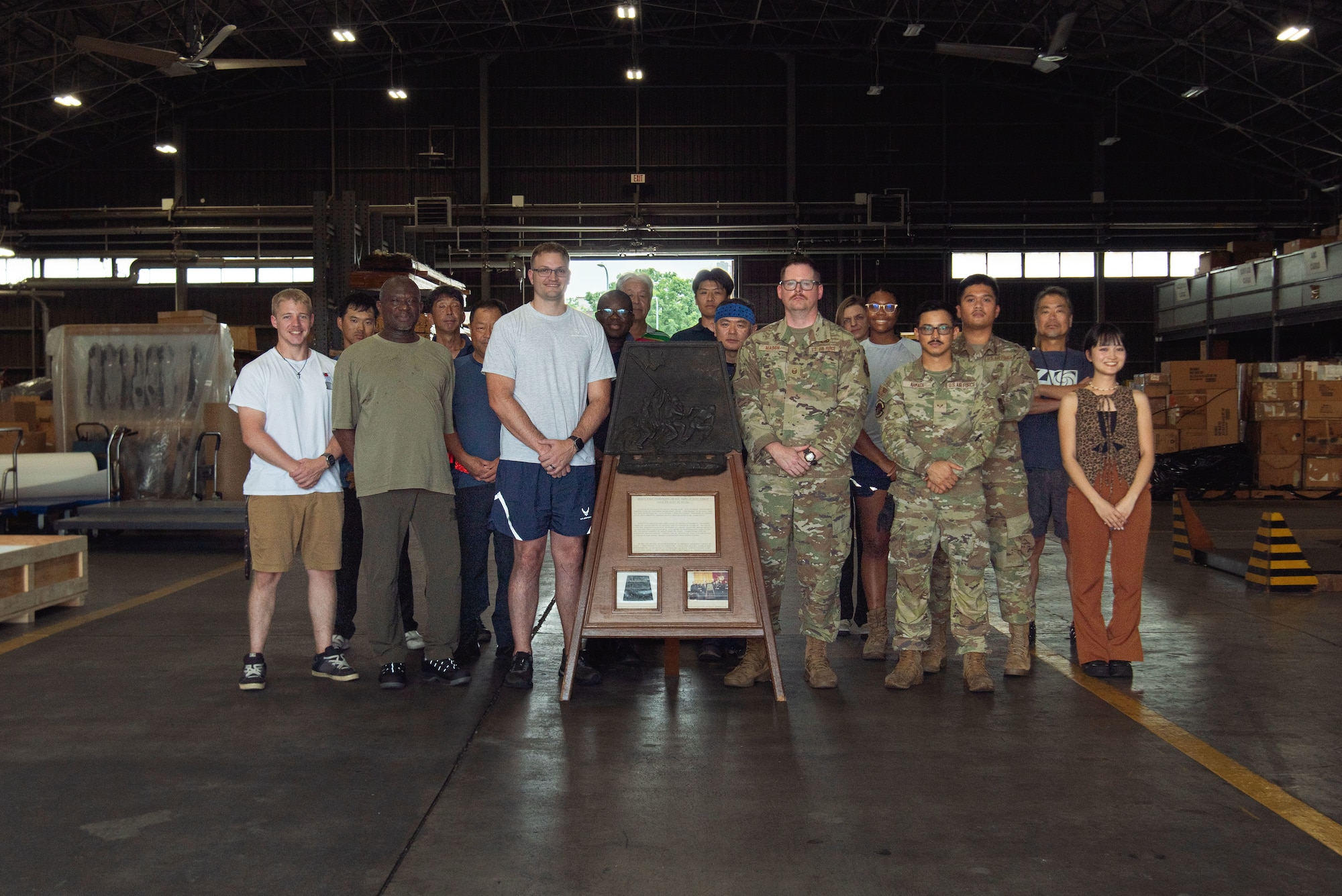 Personnel pose for a photo behind a commemorative plaque