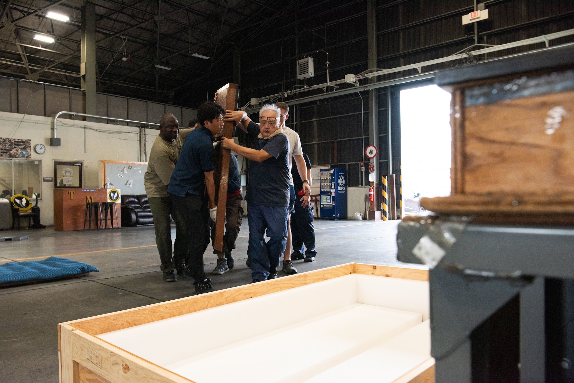 Personnel carry a plaque towards a crate