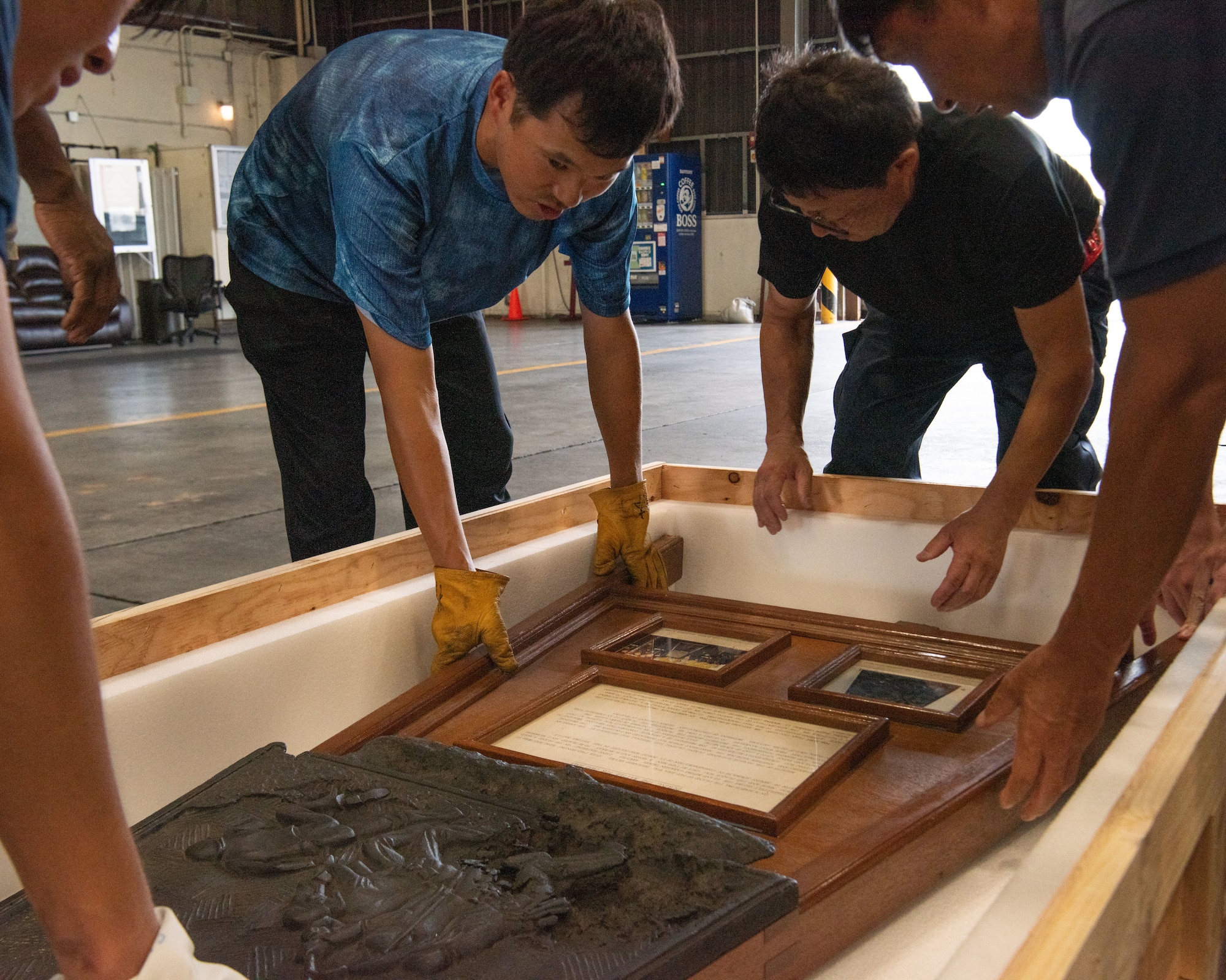 A group of personnel place a plaque into a crate