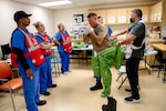 Oregon Army National Guard Sgt. Aaron Stiner, assigned to the 102nd CERFP, demonstrates the procedures for removing a coverall hazard suit with members of the Kaiser Permanente Sunnyside Medical Center staff taking part in a mass casualty training event at the Kaiser Permanente Sunnyside Medical Center on September 16, 2025, in Clackamas, Oregon. The medical personnel and other first responders, along with members of the Oregon National Guard 102nd Chemical Biological Radiological Nuclear (CBRN) Defense Enhanced Response Force Package (CERFP), collaborated during the exercise, which aimed to develop a response to a real-world incident, identify gaps, and improve response procedures.