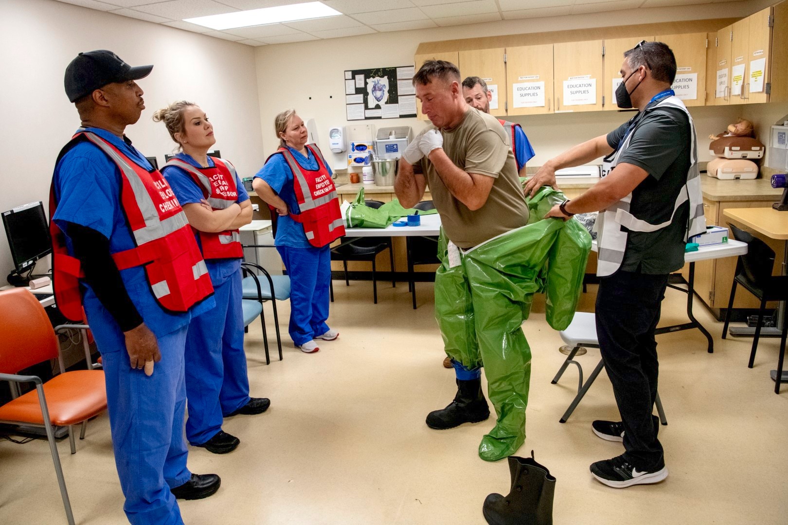 Oregon Army National Guard Sgt. Aaron Stiner, assigned to the 102nd CERFP, demonstrates the procedures for removing a coverall hazard suit with members of the Kaiser Permanente Sunnyside Medical Center staff taking part in a mass casualty training event at the Kaiser Permanente Sunnyside Medical Center on September 16, 2025, in Clackamas, Oregon.