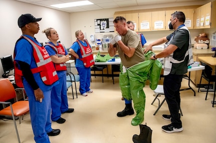 Oregon Army National Guard Sgt. Aaron Stiner, assigned to the 102nd CERFP, demonstrates the procedures for removing a coverall hazard suit with members of the Kaiser Permanente Sunnyside Medical Center staff taking part in a mass casualty training event at the Kaiser Permanente Sunnyside Medical Center on September 16, 2025, in Clackamas, Oregon.