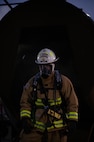 Chief Master Sgt. Anik Emery exits an aircraft fire training facility during a live structure fire exercise at Minot Air Force Base, North Dakota, Sept. 16, 2025. It's customary for firefighters to wear helmets that indicate their rank: white for chief, red for crew chief or captain, black for lieutenant and yellow for fireman. (U.S. Air Force photo by Senior Airman Alyssa Bankston)