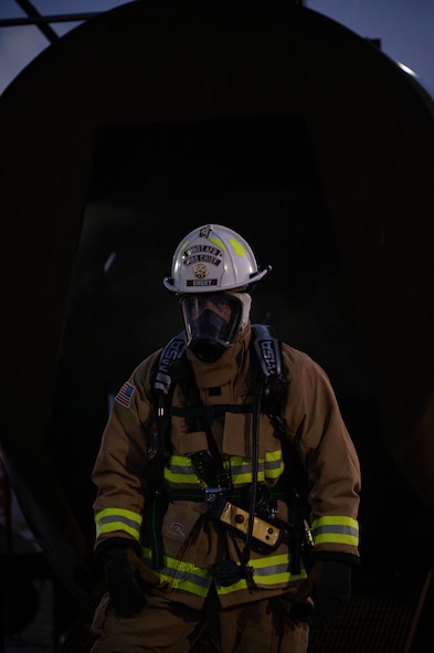 Chief Master Sgt. Anik Emery exits an aircraft fire training facility during a live structure fire exercise at Minot Air Force Base, North Dakota, Sept. 16, 2025. It's customary for firefighters to wear helmets that indicate their rank: white for chief, red for crew chief or captain, black for lieutenant and yellow for fireman. (U.S. Air Force photo by Senior Airman Alyssa Bankston)