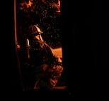 A 5th Civil Engineer Squadron fire protection specialist extinguishes an ongoing fire during a live jet fire exercise at Minot Air Force Base, North Dakota, Sept. 16, 2025. A fire hose's typical operating pressure ranges from 116 to 290 pounds per square inch. (U.S. Air Force photo by Senior Airman Alyssa Bankston)