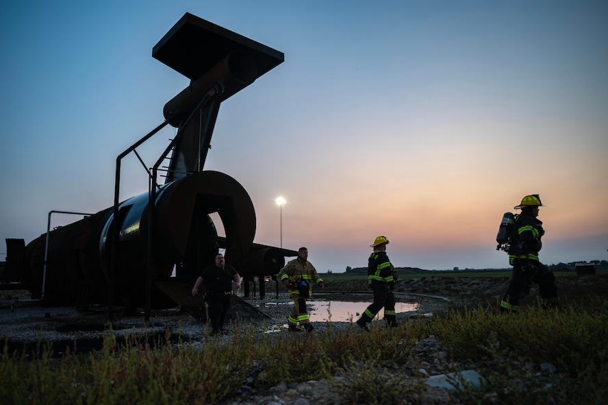 The 5th Civil Engineer Squadron’s fire protection team exits an aircraft fire training facility before a live structure fire exercise at Minot Air Force Base, North Dakota, Sept. 16, 2025. Military firefighters protect the environment, people and property against fires and disasters. (U.S. Air Force photo by Senior Airman Alyssa Bankston)