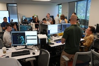 people standing and sitting looking at computer screens