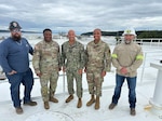 RDML Bresnihan stands in the center of a group photo taken atop a fuel storage tank at a DLA Energy Americas North facility in Anchorage. Standing with RDML Bresnihan are Col. Simmons, Maj. Stephens, Quality Assurance Manager Brian Reed, and Anchorage Terminal Manager Mark Gilleland.