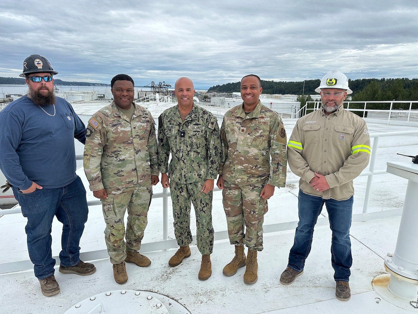 RDML Bresnihan stands in the center of a group photo taken atop a fuel storage tank at a DLA Energy Americas North facility in Anchorage. Standing with RDML Bresnihan are Col. Simmons, Maj. Stephens, Quality Assurance Manager Brian Reed, and Anchorage Terminal Manager Mark Gilleland.