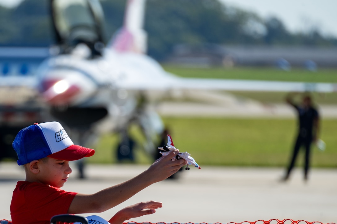 A young spectator plays with a toy Thunderbird aircraft before the 2025 Joint Base Andrews Air Show.