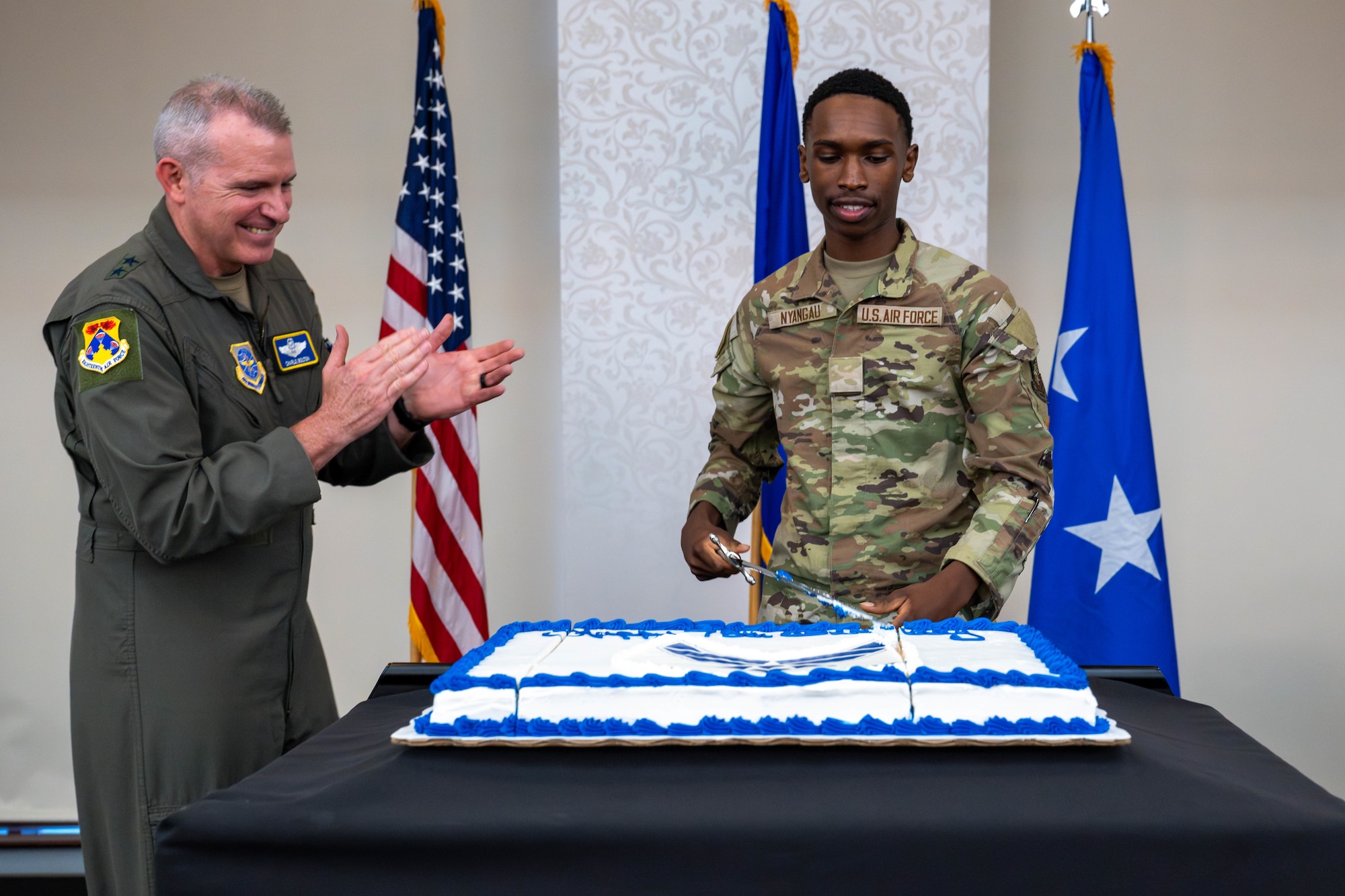 Airman cuts cake while General applauds