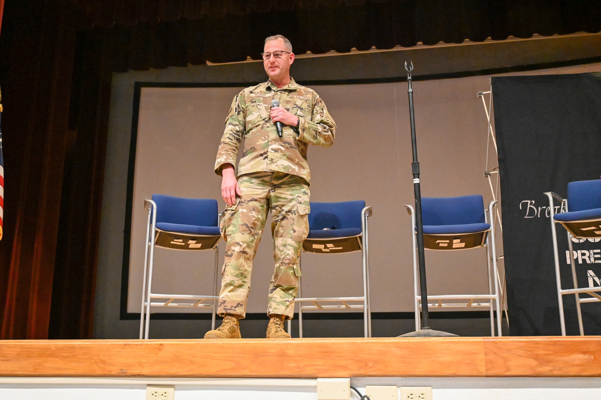 A man in uniform stands on stage and talks to the audience