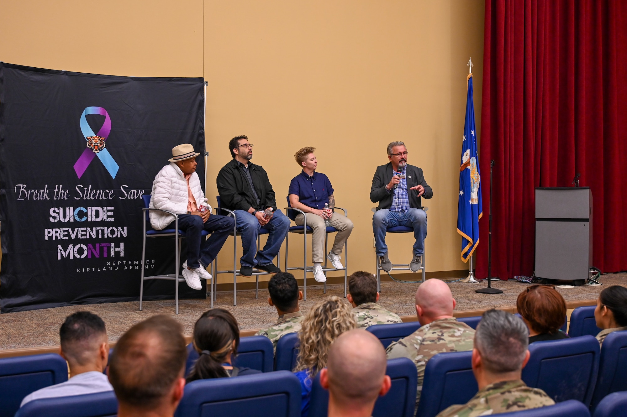 Four people sitting in chairs on stage are talking to the audience