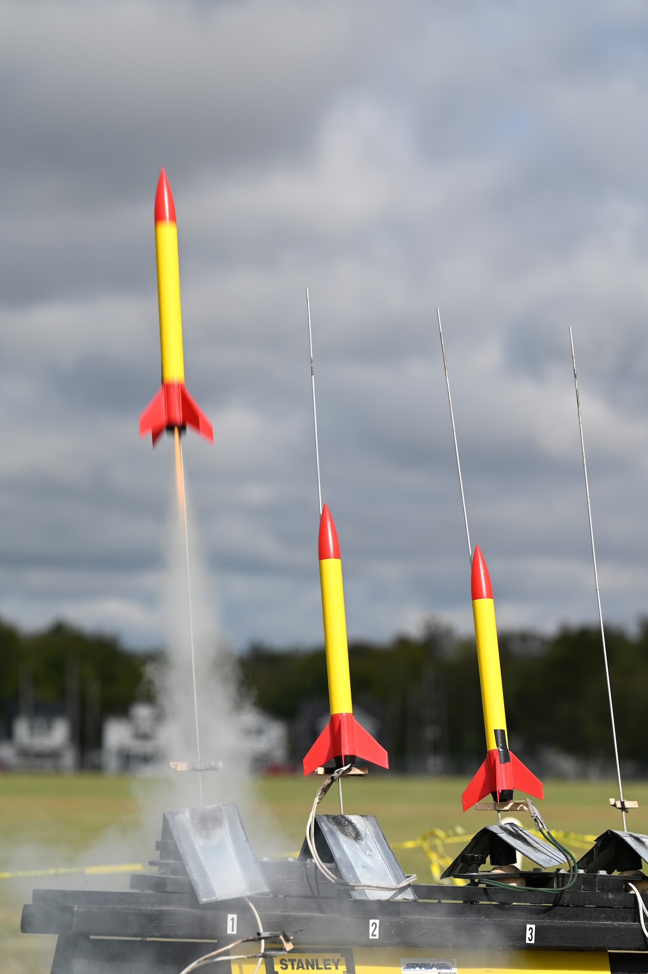 A row of three rockets launching on the front lawn of the National Museum of the U.S. Air Force.