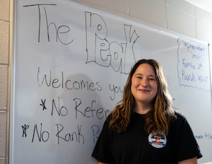Amanda Walz stands in front of the Peak Pantry whiteboard welcoming sign.