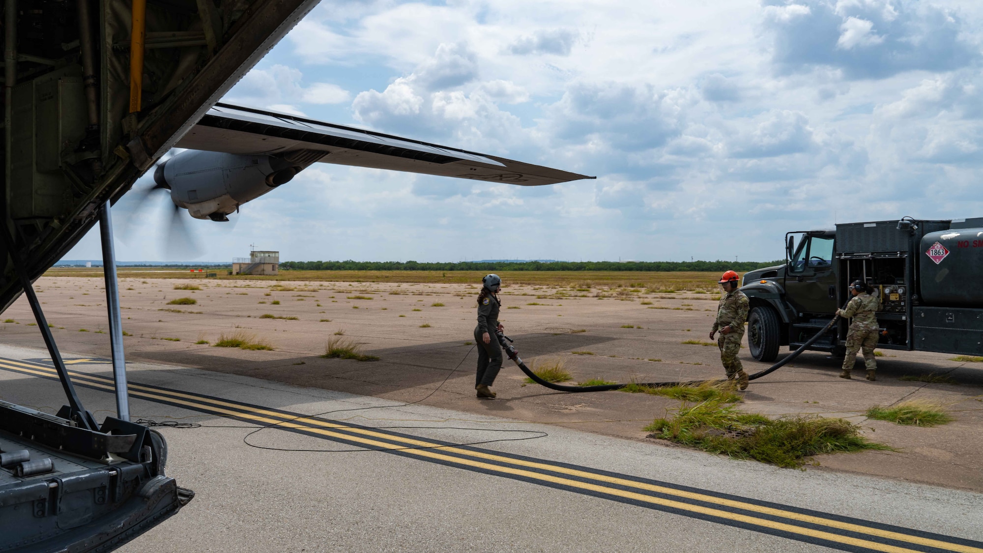 U.S. Air Force Senior Airman Tess Pouliot, 40th Airlift Squadron loadmaster, supports a hot-pit refuel of a C-130J Super Hercules assigned to the 317th Airlift Wing, at Tye Landing Zone, Dyess Air Force Base, Texas, Aug. 26, 2025. A hot-pit refuel involves transferring fuel to or from the aircraft while engines are running, minimizing downtime and maximizing the aircraft's availability. (U.S. Air Force photo by Senior Airman Jade M. Caldwell)