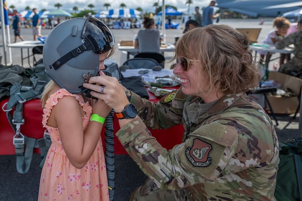 Airmen putting a helmet on child.