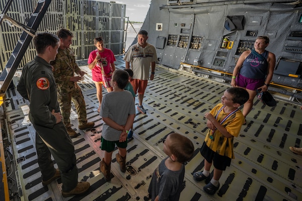 Airmen and civilians speak inside of an aircraft.