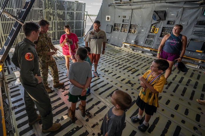 Airmen and civilians speak inside of an aircraft.
