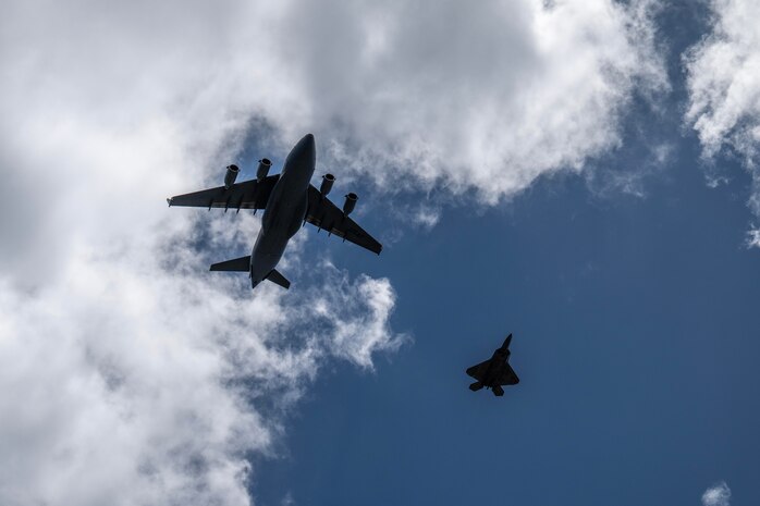 A cargo aircraft and a fighter jet fly in the sky.