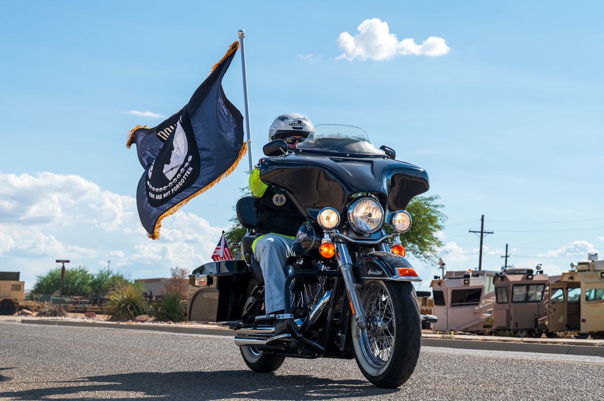 Robby Johnson, retired Airman, rides his motorcycle with the Prisoner of War and Missing in Action flag at Davis-Monthan Air Force Base, Arizona, Sept. 18, 2025. Johnson performed the first two laps of the 24-hour POW/MIA remembrance run. (U.S. Air Force photo by Senior Airman Jasmyne Bridgers-Matos)