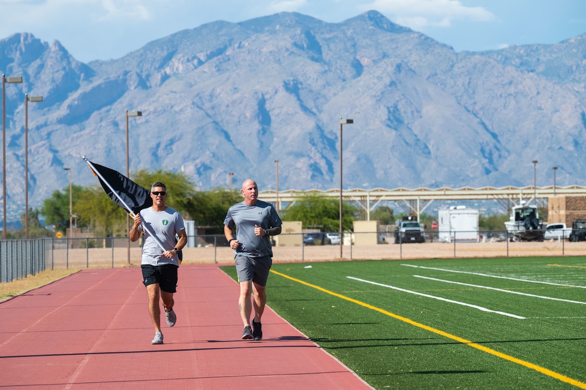 U.S. Air Force Col. Jose Cabrera, 355th Wing commander, runs with the Prisoner of War and Missing in Action flag during the POW/MIA remembrance run at Davis-Monthan Air Force Base, Arizona, Sept. 18, 2025. The Desert Lightning Team paid tribute to service members who were prisoners of war and those who remain missing in action by carrying the POW/MIA flag for 24 hours, ensuring their sacrifices are always remembered. (U.S. Air Force photo by Senior Airman Jasmyne Bridgers-Matos)