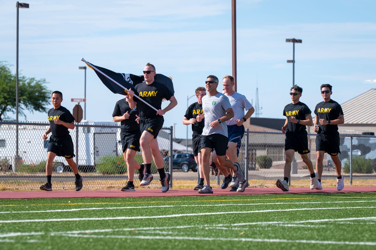 U.S. Airmen assigned to the 355th Wing and Soldiers assigned to the 2nd Battalion, 12th Infantry Regiment, run with the Prisoner of War and Missing in Action flag at Davis-Monthan Air Force Base, Arizona, Sept. 18, 2025. Teams rotated to keep the flag in motion for 24 hours. (U.S. Air Force photo by Senior Airman Jasmyne Bridgers-Matos)