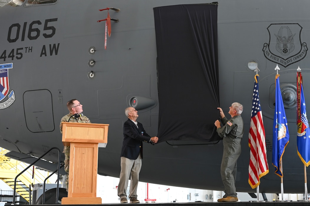 U.S. Air Force Reserve Col. Douglas A. Perry Jr., right, 445th Airlift Wing commander, and retired Maj. Gen. Edward Mechenbier, left, Vietnam veteran and guest speaker, unveil the newly re-designated name of the C-17 Globemaster III with tail number 99-0165 at Wright-Patterson Air Force Base, Ohio, Sept. 19, 2025. The ceremony was part of Operation Honor, paying tribute to the bond between the 445th Airlift Wing and the original C-141 Starlifter Hanoi Taxi, which repatriated American POWs from Vietnam and brought them back home. (U.S. Air Force photo by Staff Sgt. Johnathan Quiñones)