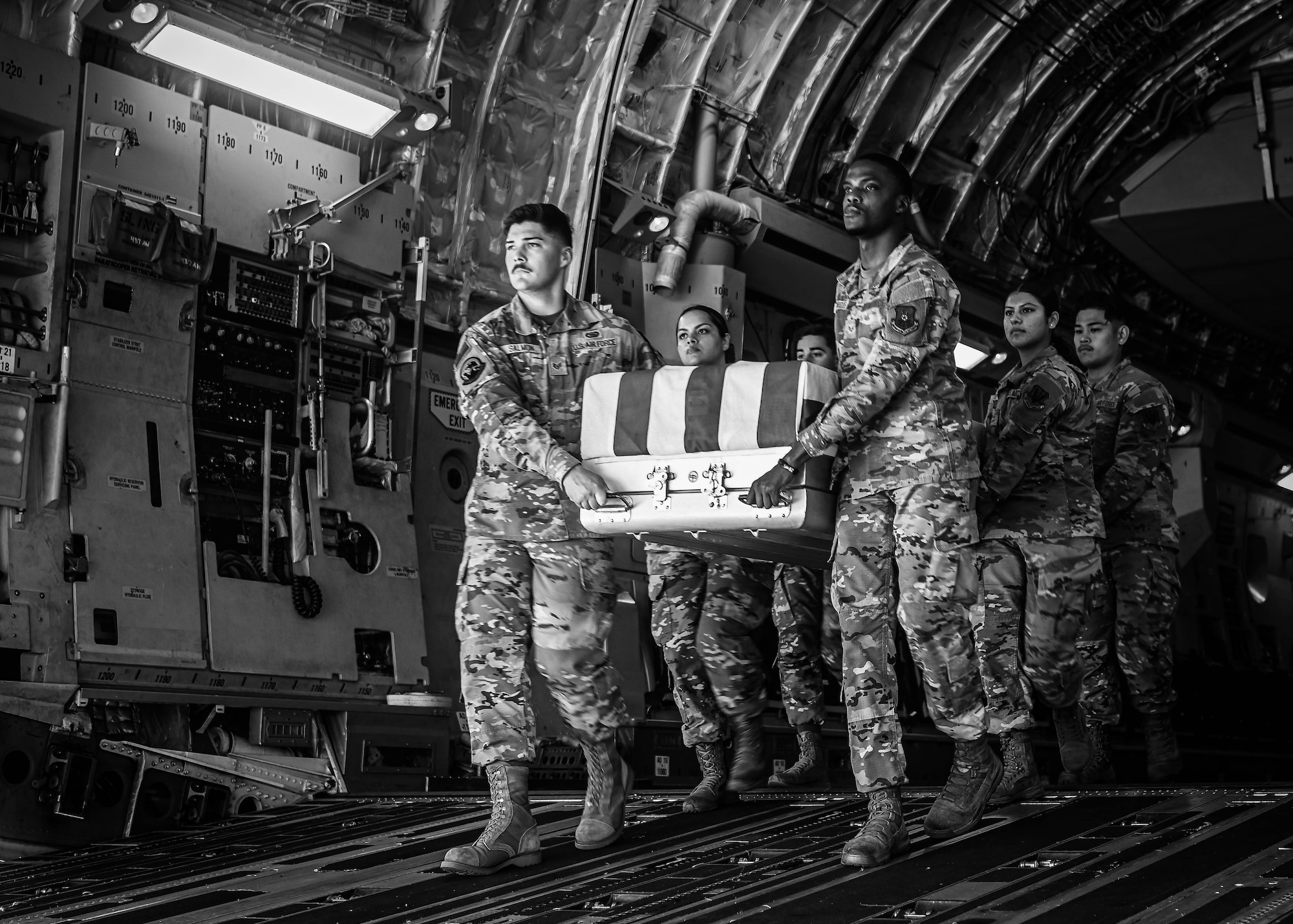 Airmen make their way down the ramp of a C-17 Globemaster III while carrying the remains of an unidentified service member during an Honorable Carry Ceremony at Offutt Air Force Base, Neb., July 17, 2025. The ceremony is performed to respectfully transfer the remains of service members. (U.S. Air Force photo by Daniel Martinez)