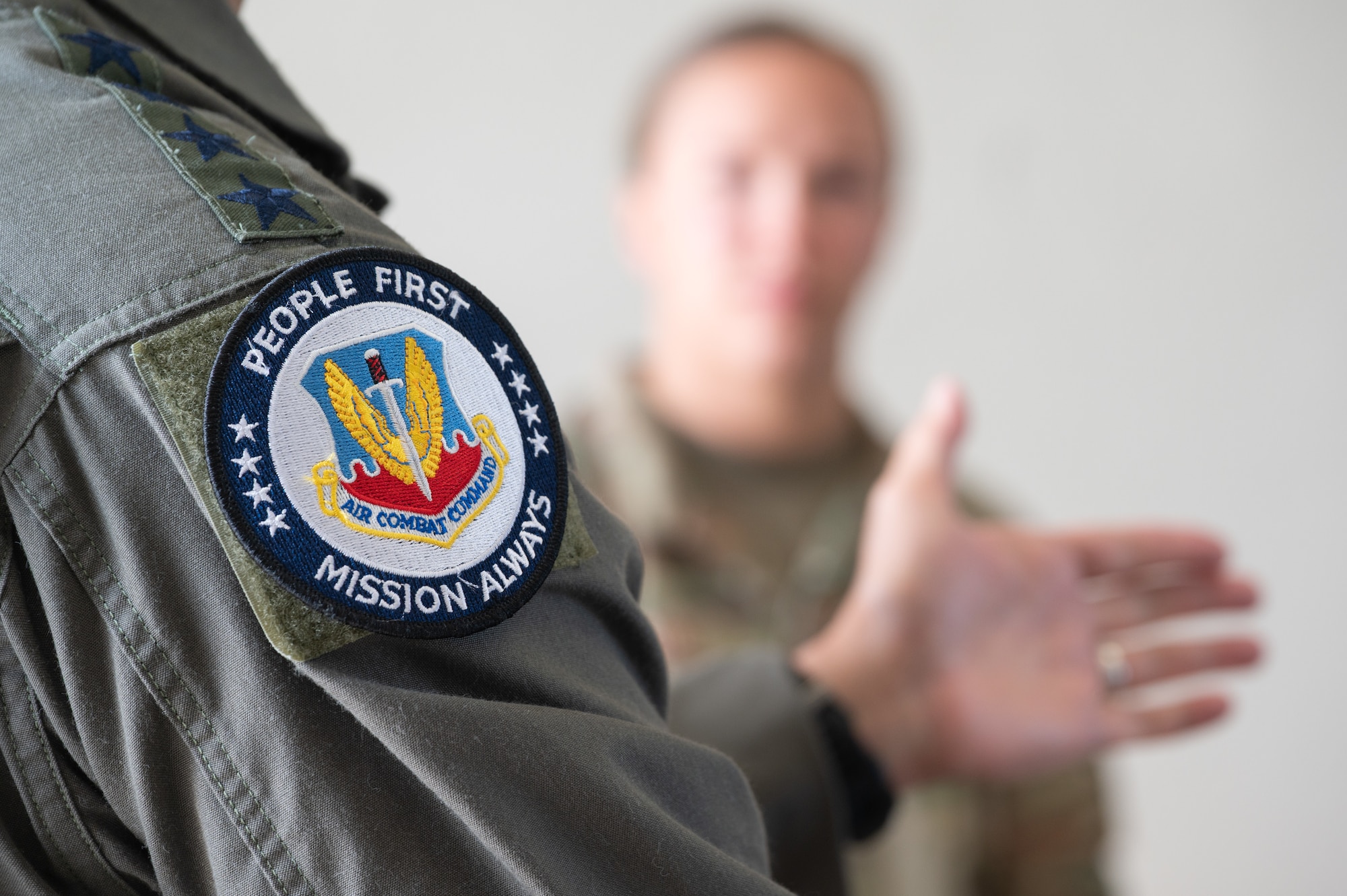 COMACC talking with another airman with his 'People First, Mission Always' patch as the main focus in the photo.