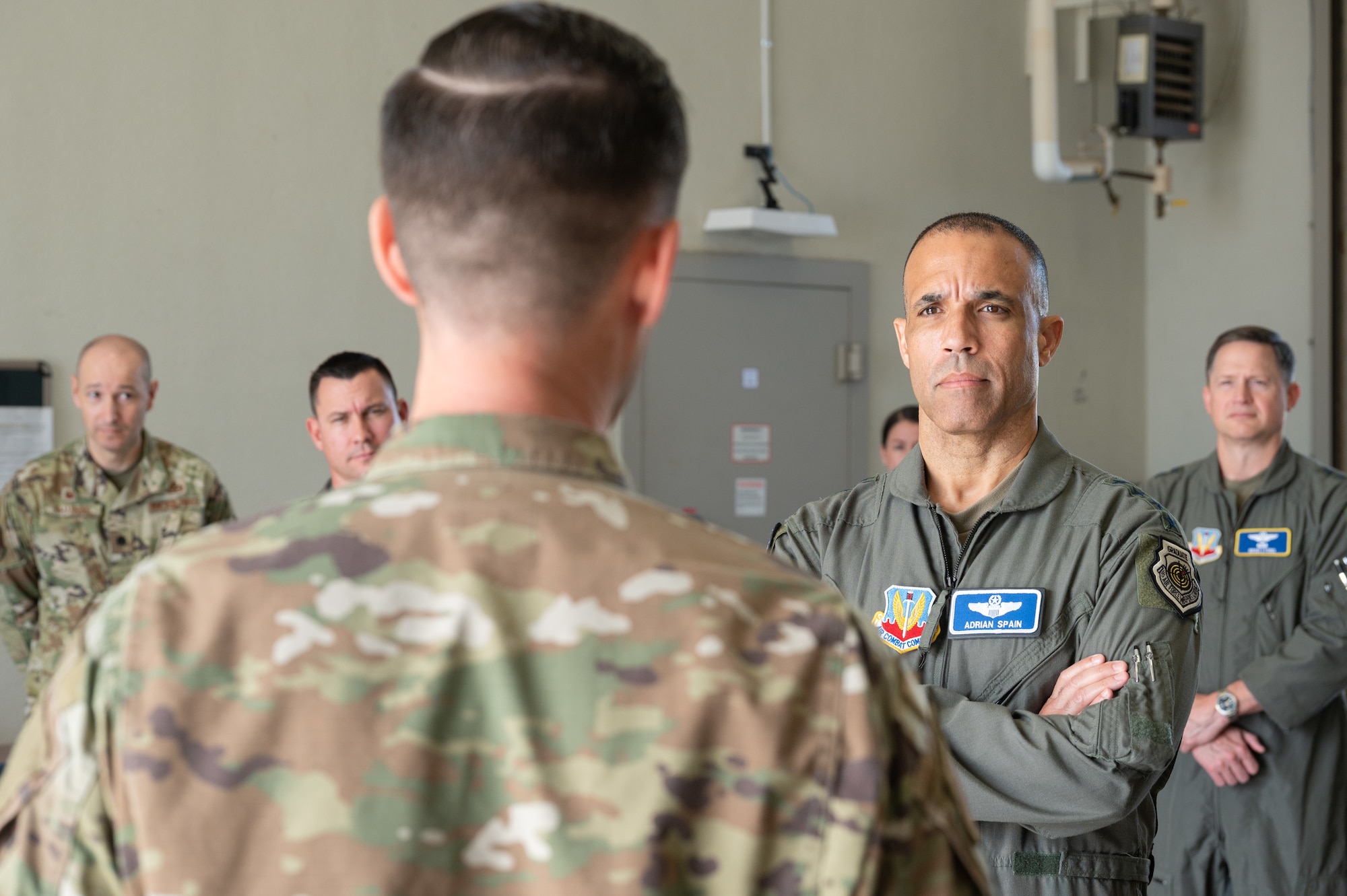 COMACC listens to an Airman talking with other service members in the background.