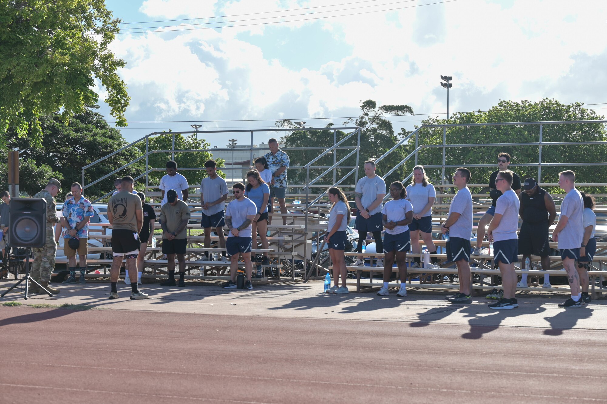 Airmen standing on bleachers during a prayer with the chaplain.