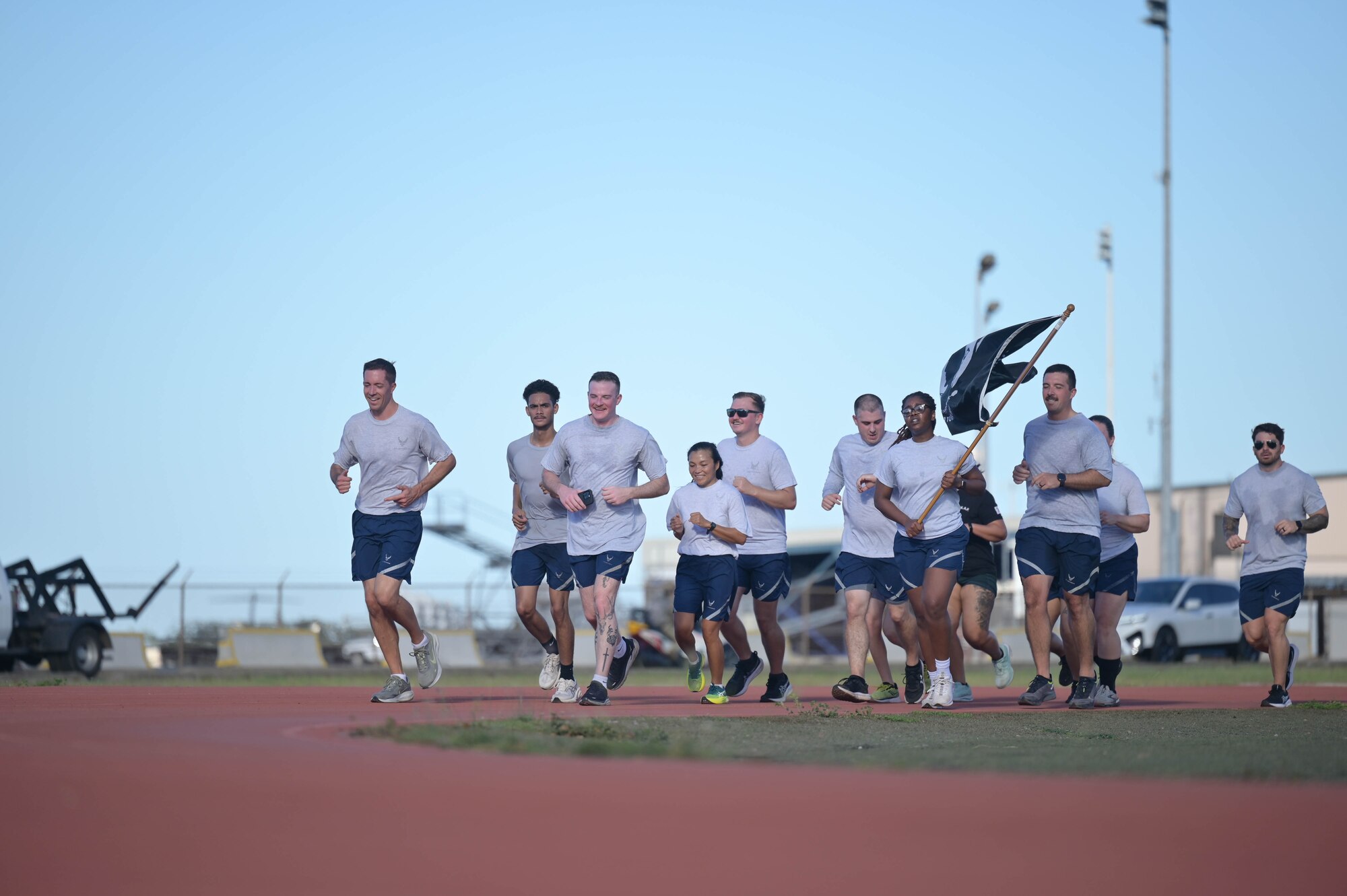 Airmen carrying POW/MIA flag while running on a track.